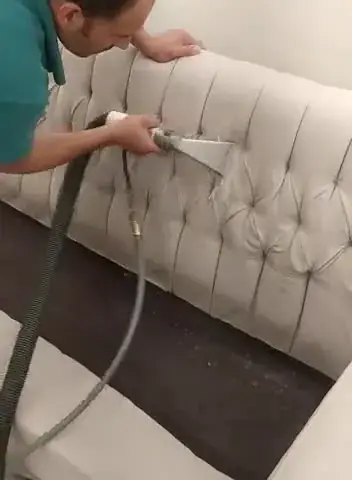 أداة الشفط على ظهر كنب أبيض مكسو بنقش الكابيتونيه